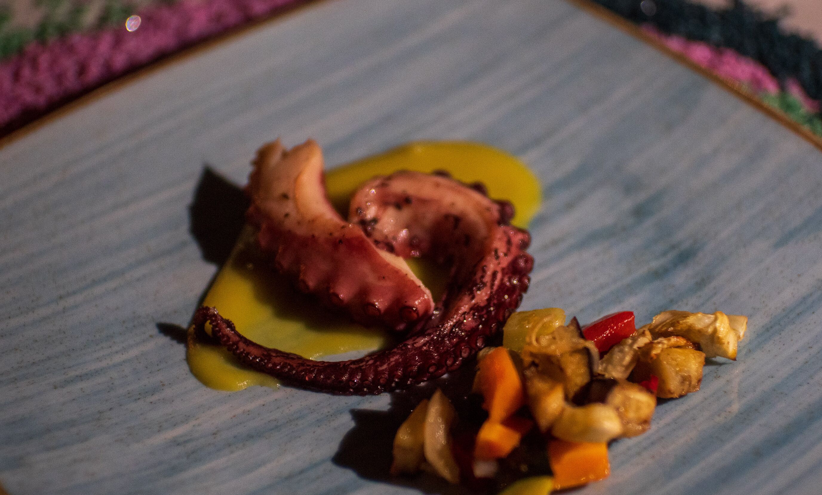 A plate with octopus tentacles, a piece of meat, and a side of vegetables.