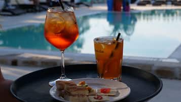 A tray with a glass of iced tea, a glass of water, and a plate of food near a pool.