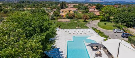 A resort with a swimming pool, outdoor seating, and a view of the surrounding landscape.