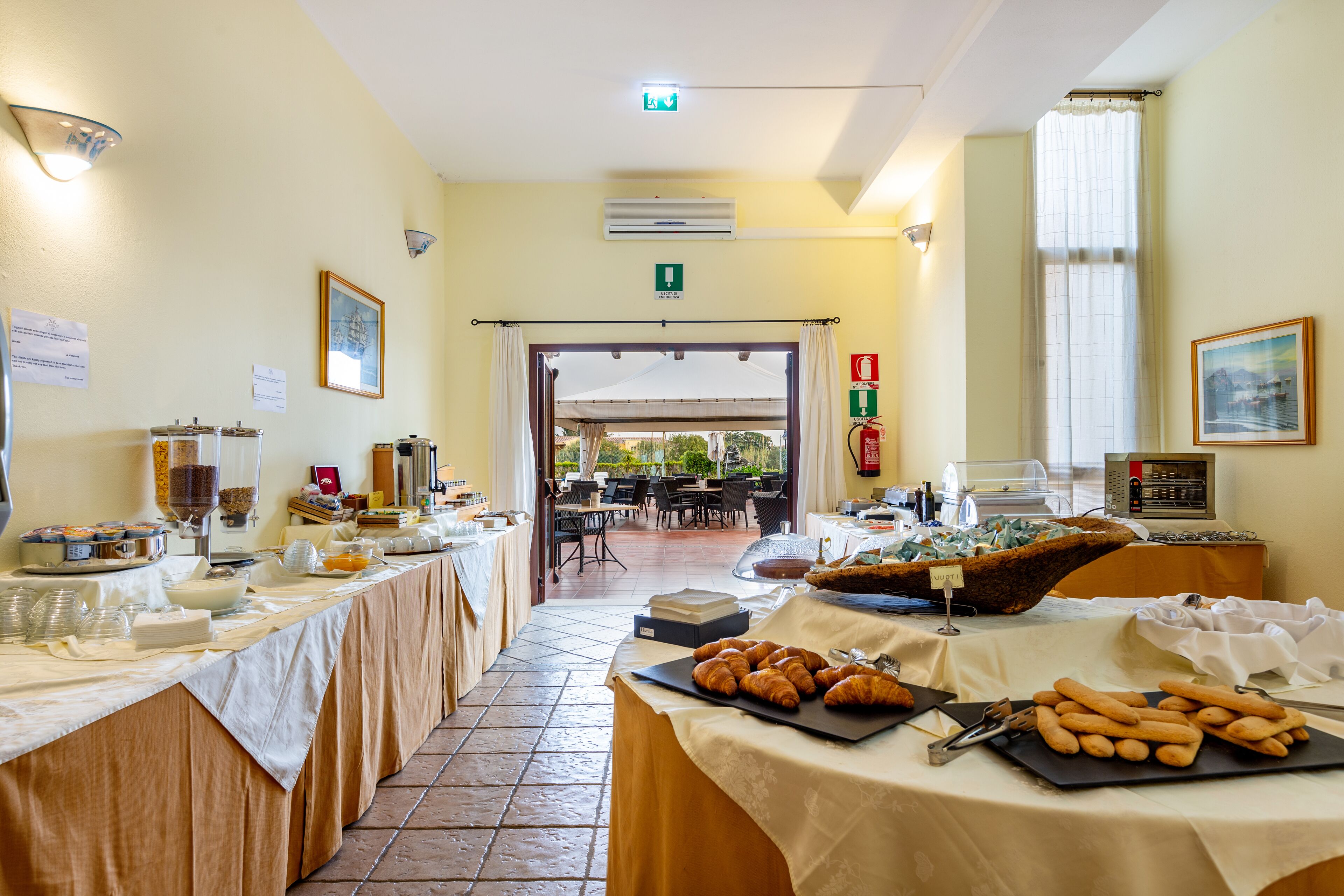 A buffet setup with various food items and a seating area in the background.