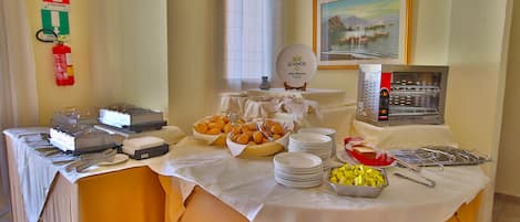 Una mesa de buffet con diversas opciones de comida y una máquina de café.