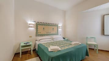 Quarto com cama, mesa de cabeceira, cadeira e luminária na parede.