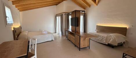 A room with two beds, a TV, and a wooden ceiling.
