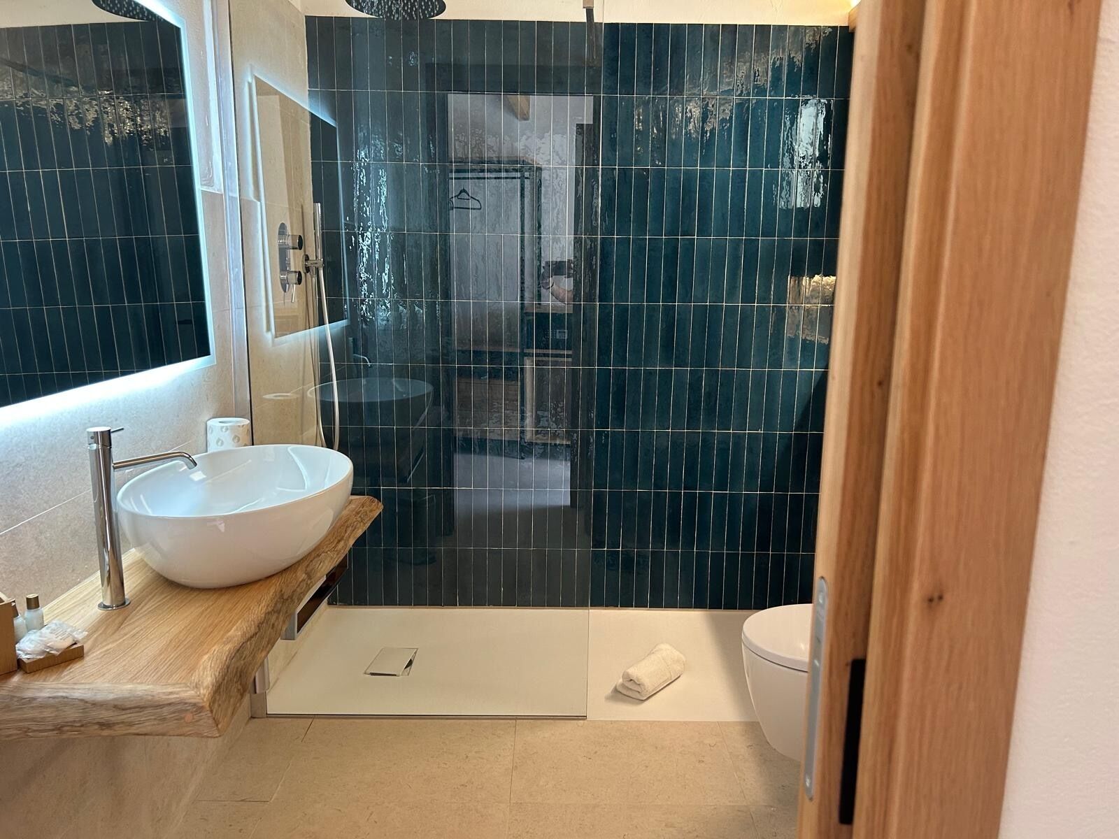 A modern bathroom with a large white sink, a glass-enclosed shower, and a wooden vanity.