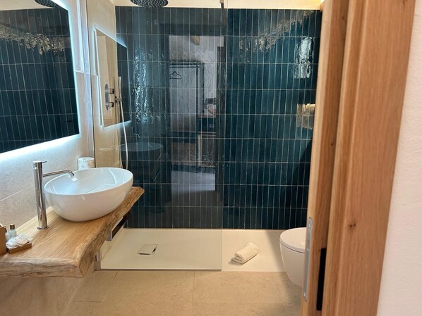 A modern bathroom with a large white sink, a glass-enclosed shower, and a wooden vanity.