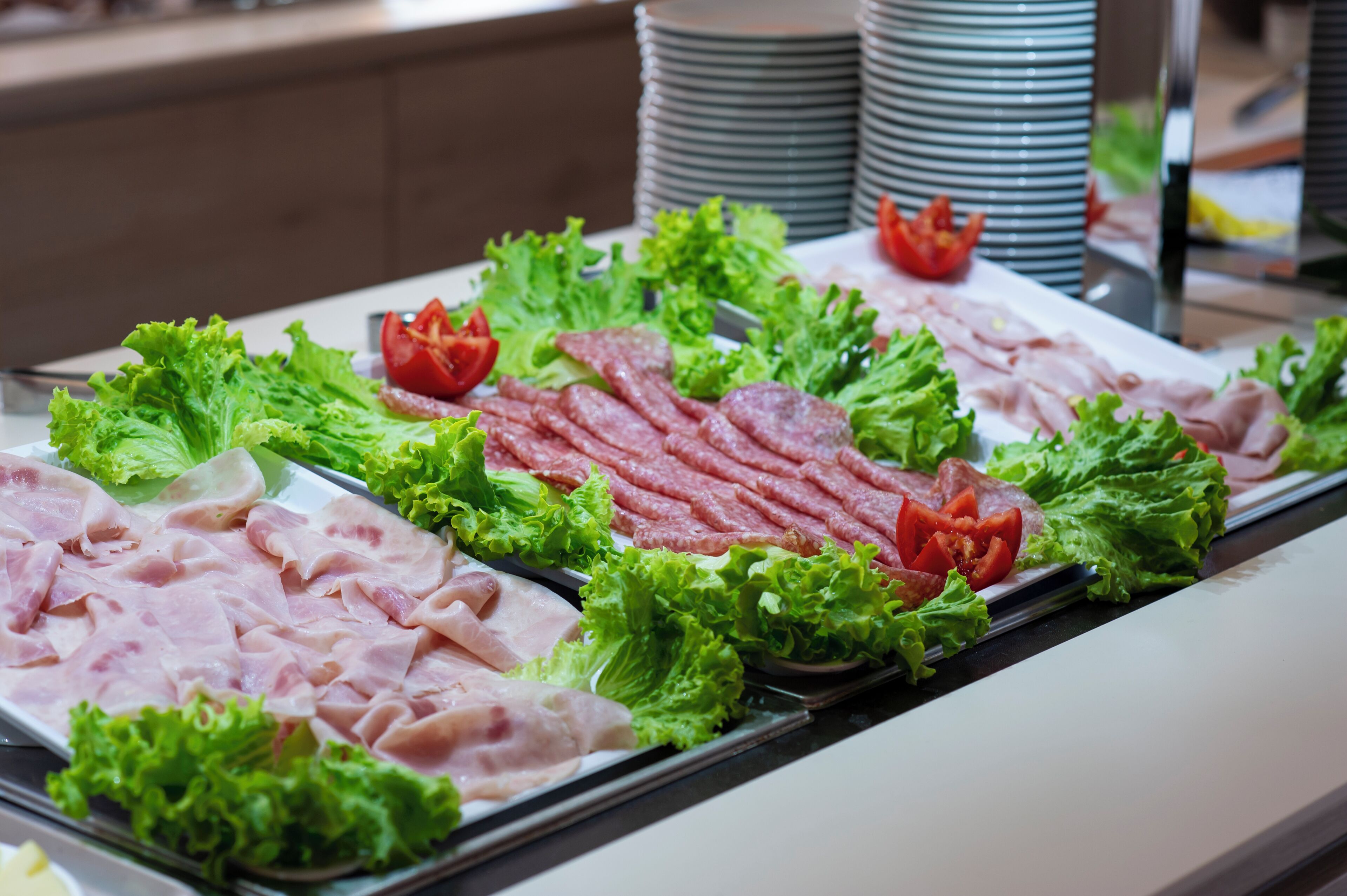 A buffet with various meats and fresh vegetables.