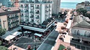 A hotel with multiple floors, outdoor seating, and a view of the sea.