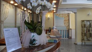 A reception desk with a vase of white orchids, a menu, and a decorative lamp.