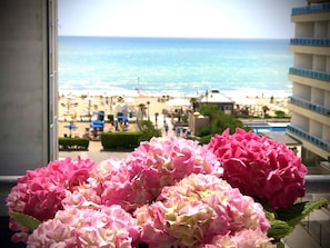 A balcony with a view of the beach and a flower arrangement. - Hotel Margherita (Jesolo)