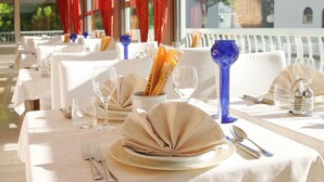 A restaurant with white tablecloths, neatly set tables, and blue glass vases.