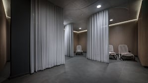 Ein moderner Flur mit vertikalen Jalousien, einer Sitzecke mit Sesseln und einer Decke mit eingelassenen Leuchten.