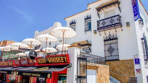 Un edificio con fachada blanca, balcones con barandillas de hierro forjado y un letrero que dice 'Irish Whiskey Bar'.