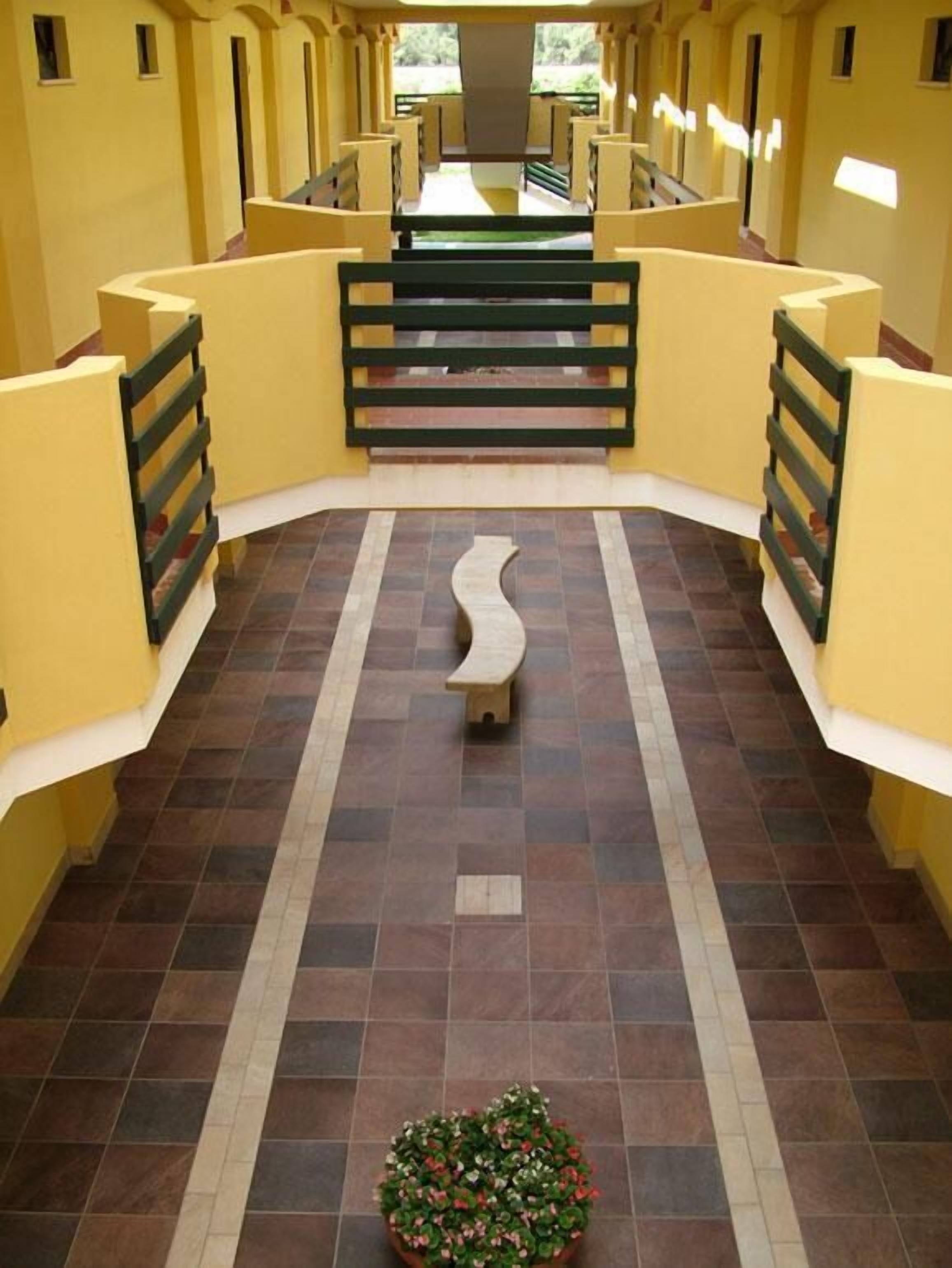 A corridor with a central bench and a small potted plant.