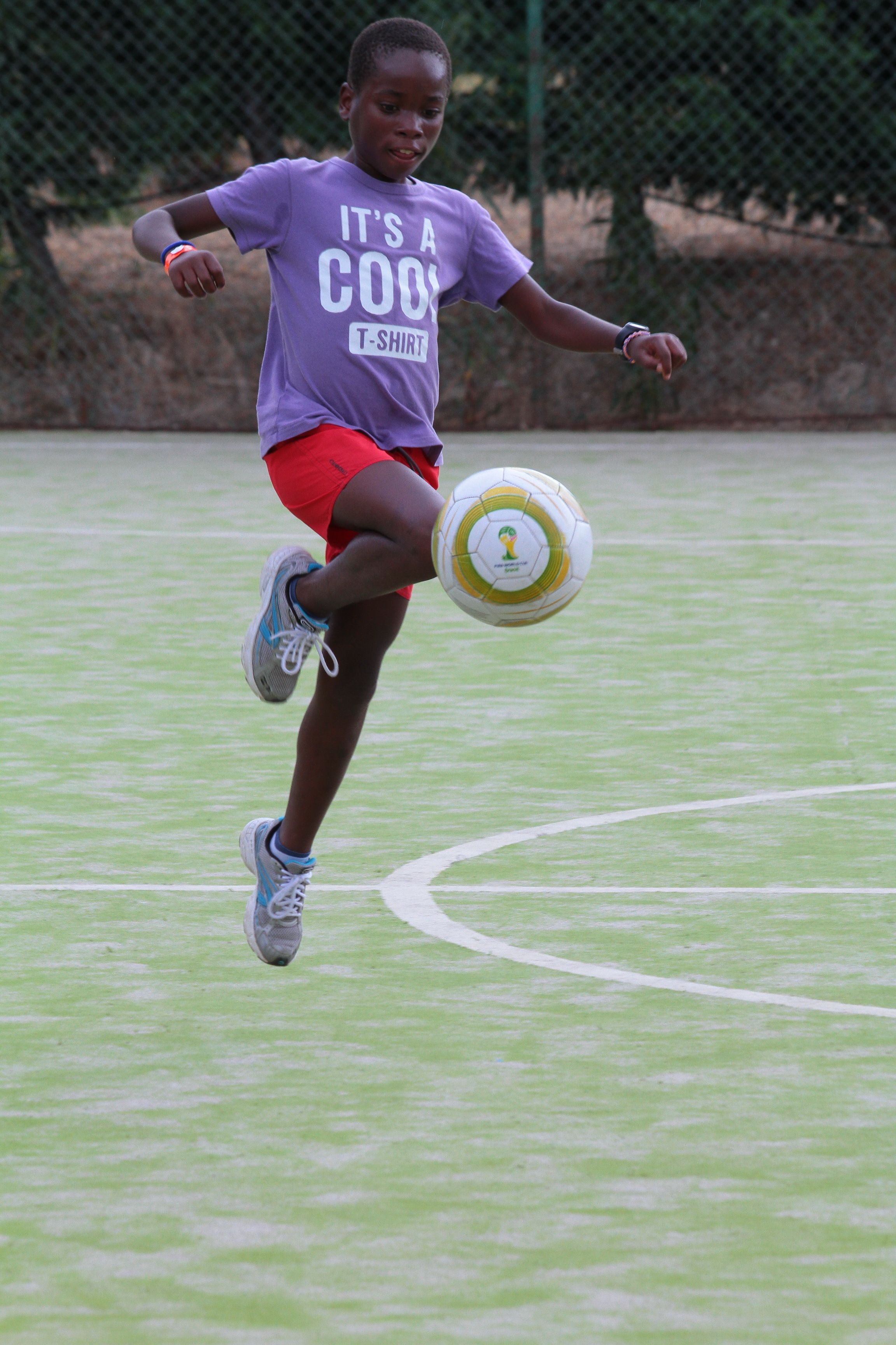 A person playing soccer on a green field with white lines.