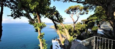 A coastal property with a staircase leading to a terrace overlooking the sea.