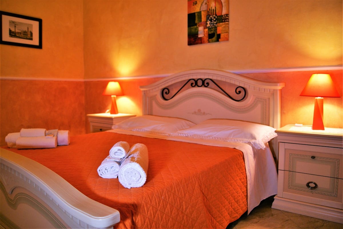 A hotel room with a bed, two bedside tables, and a nightstand.