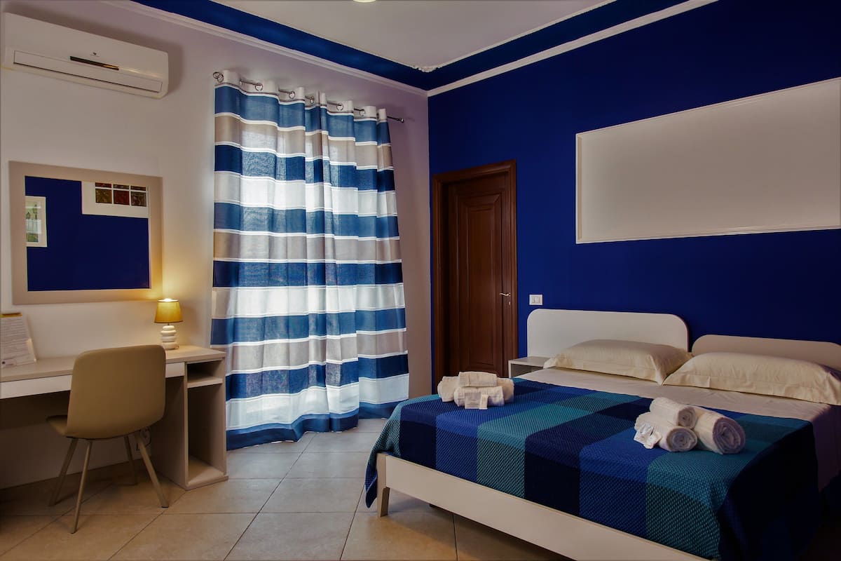 A bedroom with a bed, a desk, and a chair.