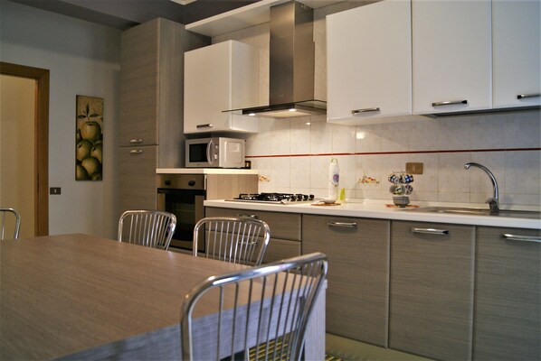 A modern kitchen with a dining table and chairs, a microwave, stove, and cabinets.