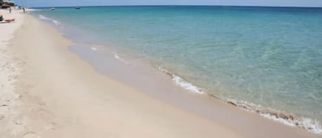 A beach with clear turquoise water and a sandy shore.