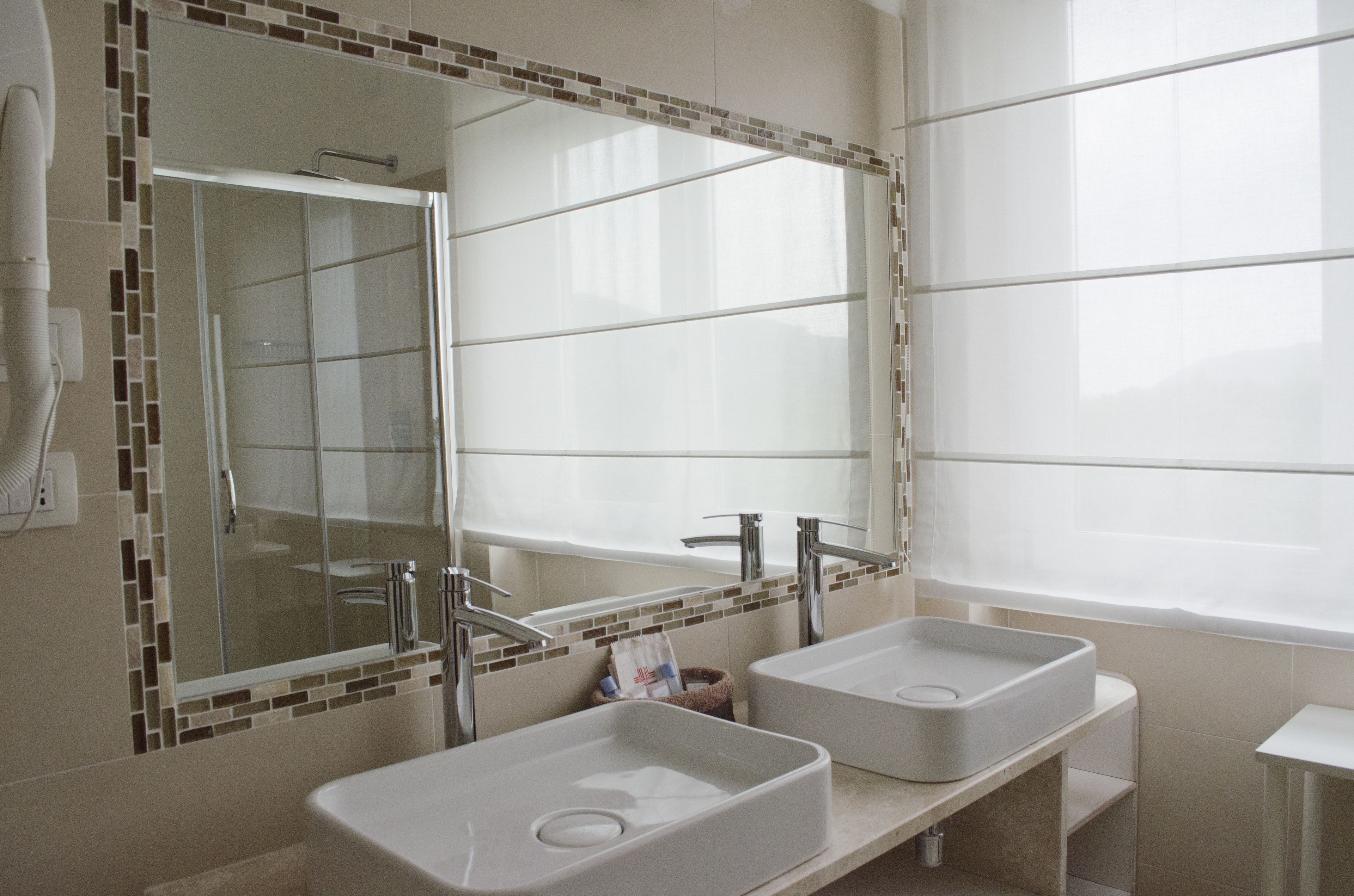 Baño con dos lavamanos, un espejo grande y una ducha.