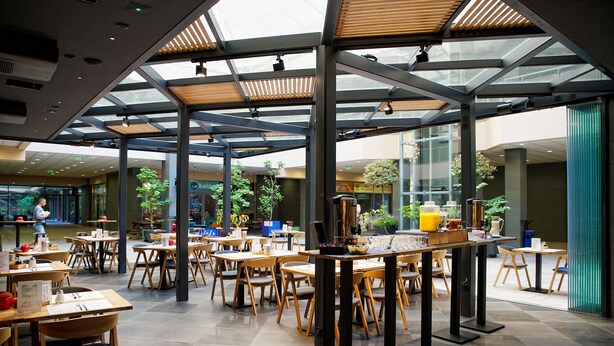 A spacious indoor dining area with multiple tables and chairs, a coffee bar, and a view of the outdoors.