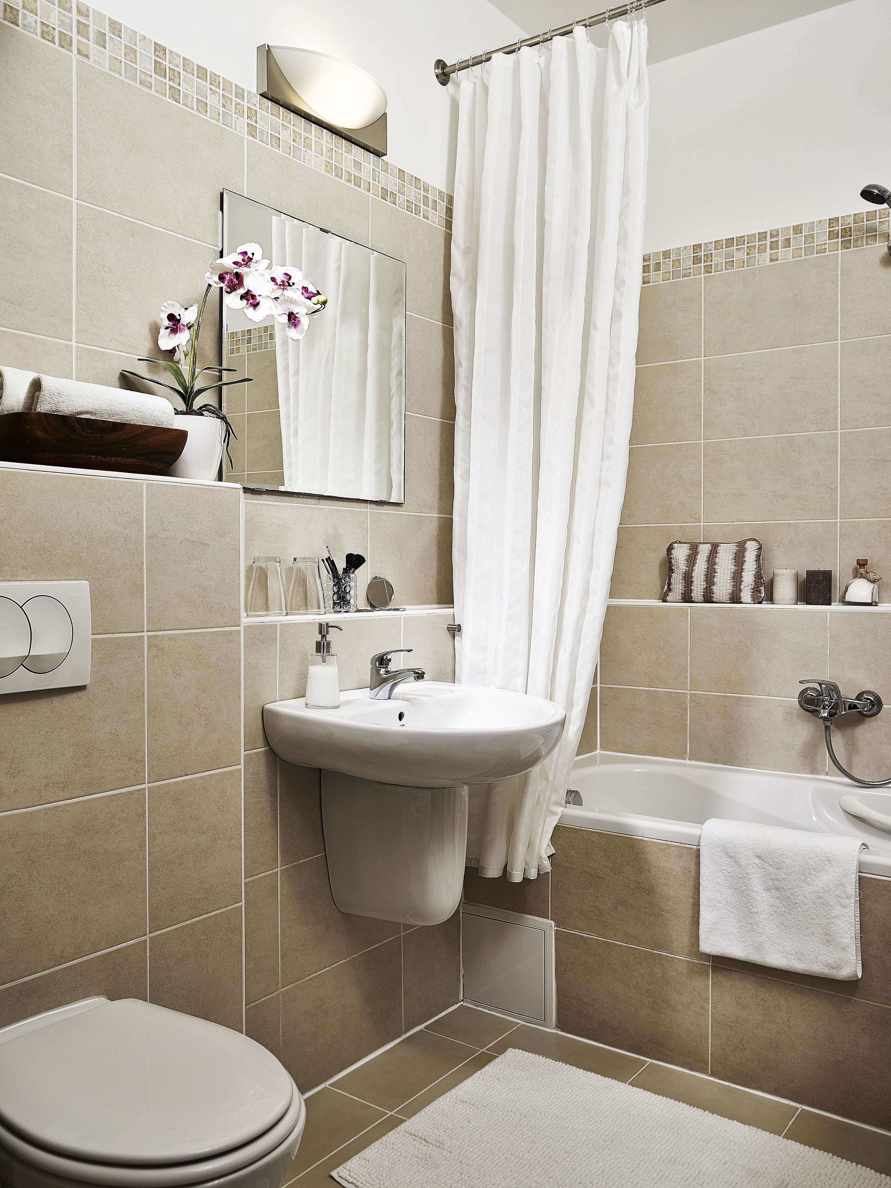 Een moderne badkamer met een wastafel, spiegel, toilet en bad.
