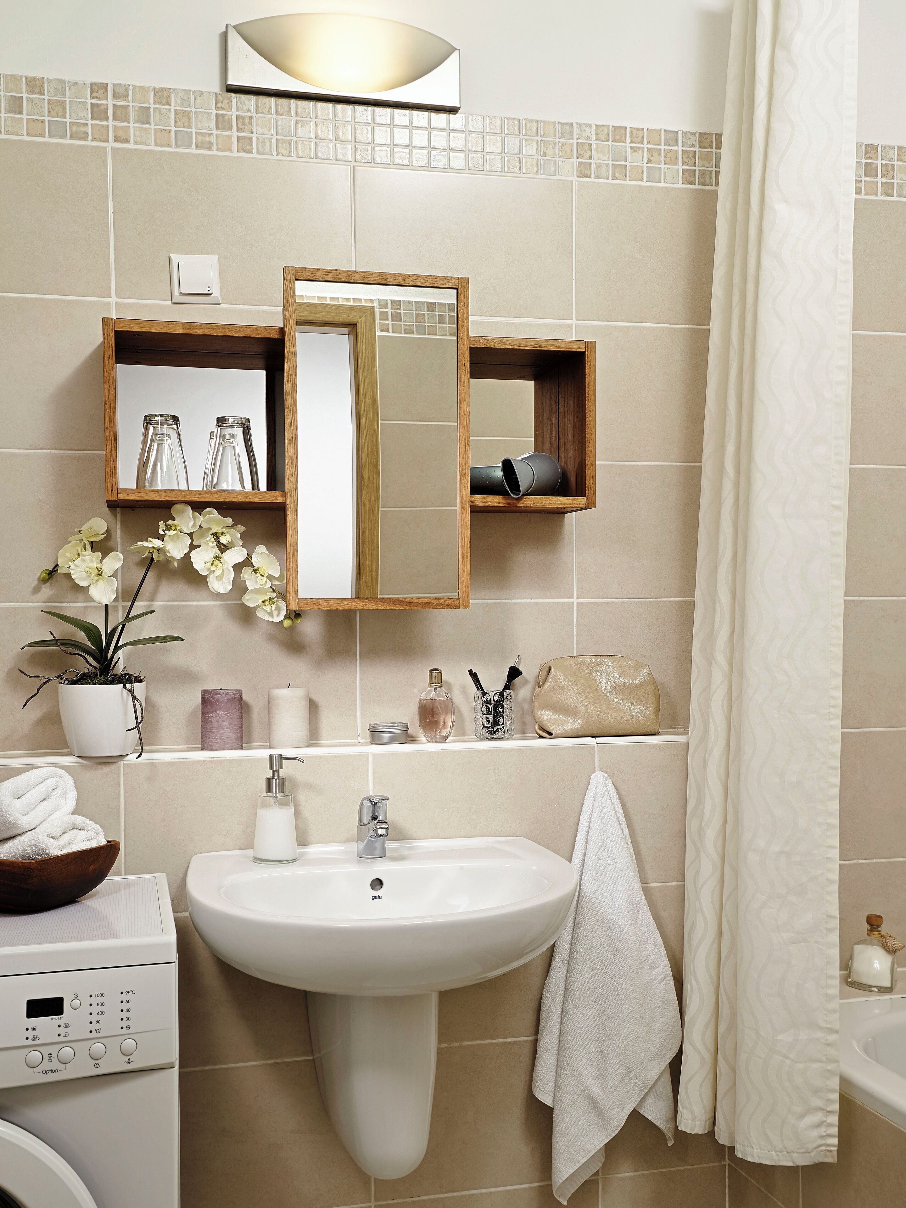 A bathroom with a sink, mirror, shelves with toiletries, a shower curtain, and a potted plant.