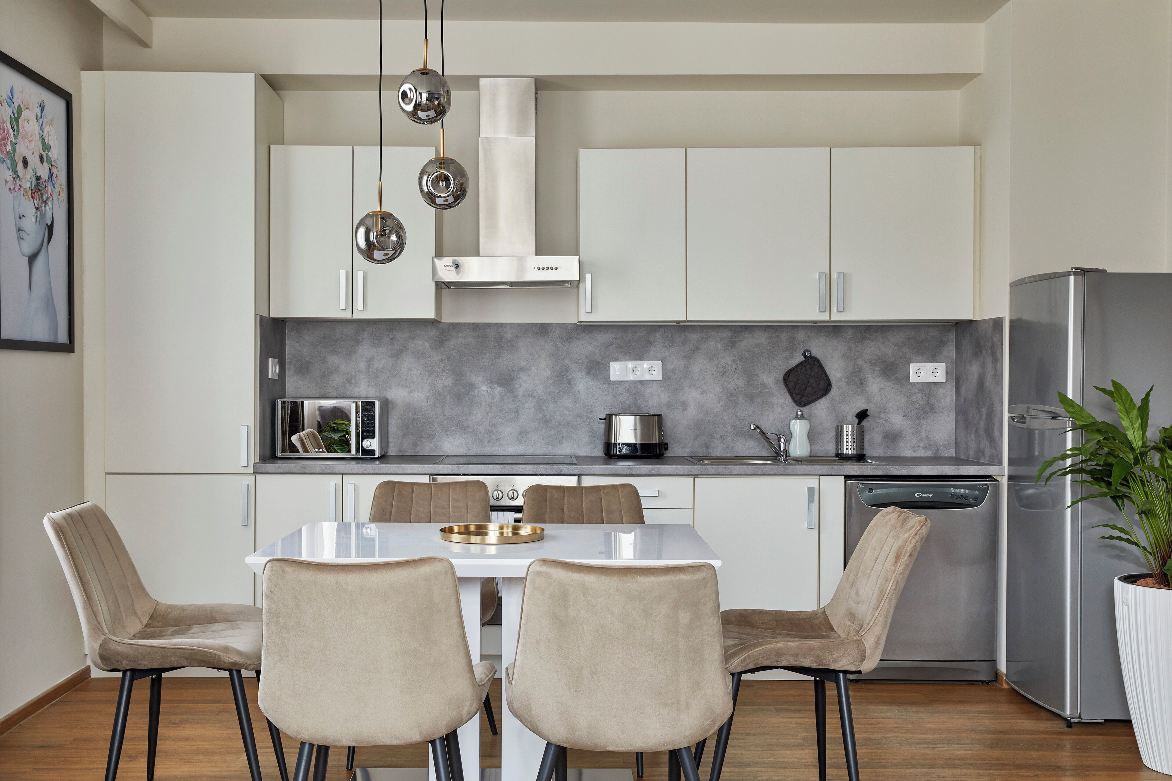 A modern kitchen with white cabinets, a stainless steel refrigerator, and a dining table with four chairs.