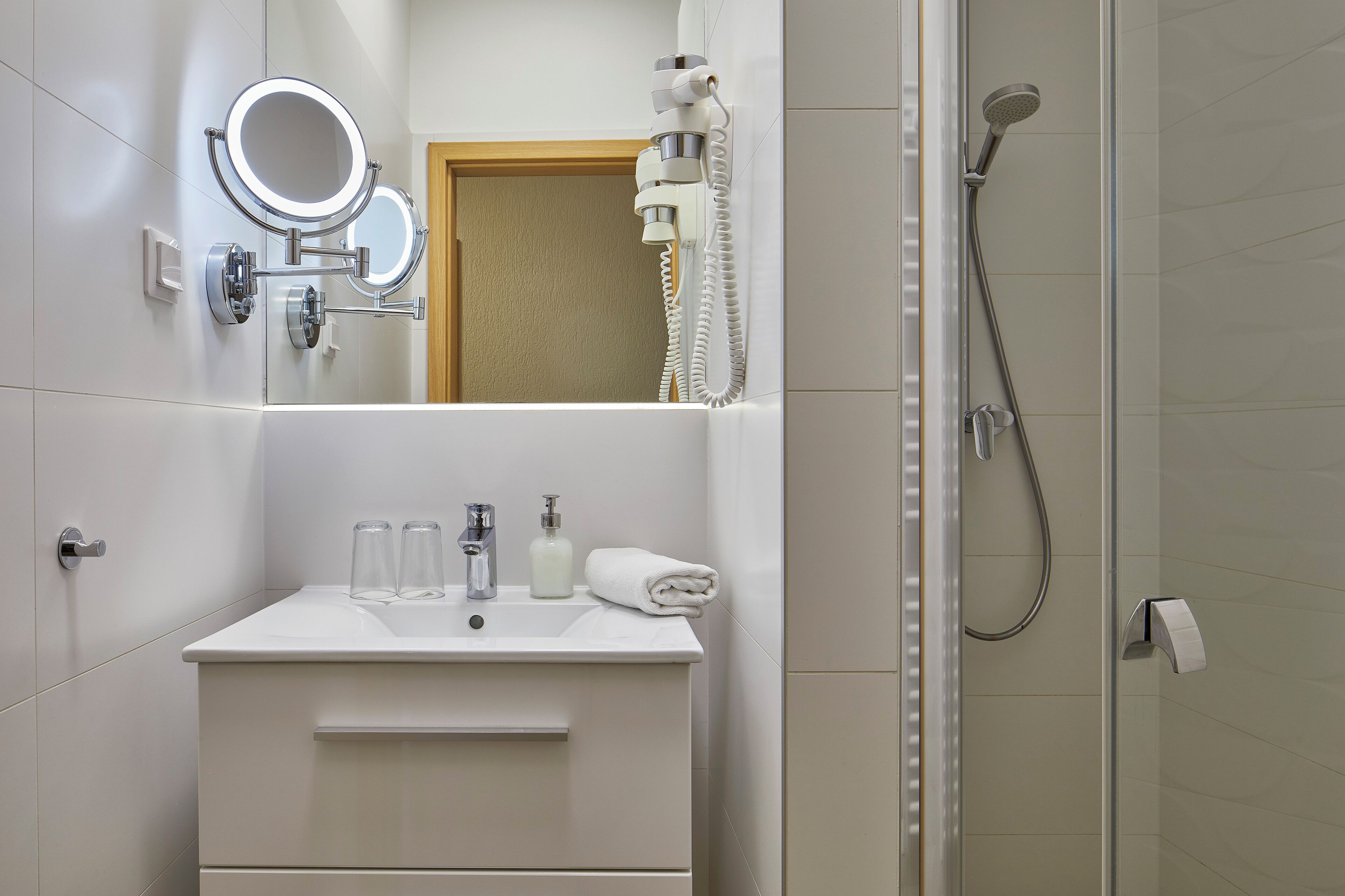 Un baño moderno con lavamanos, espejo y ducha.