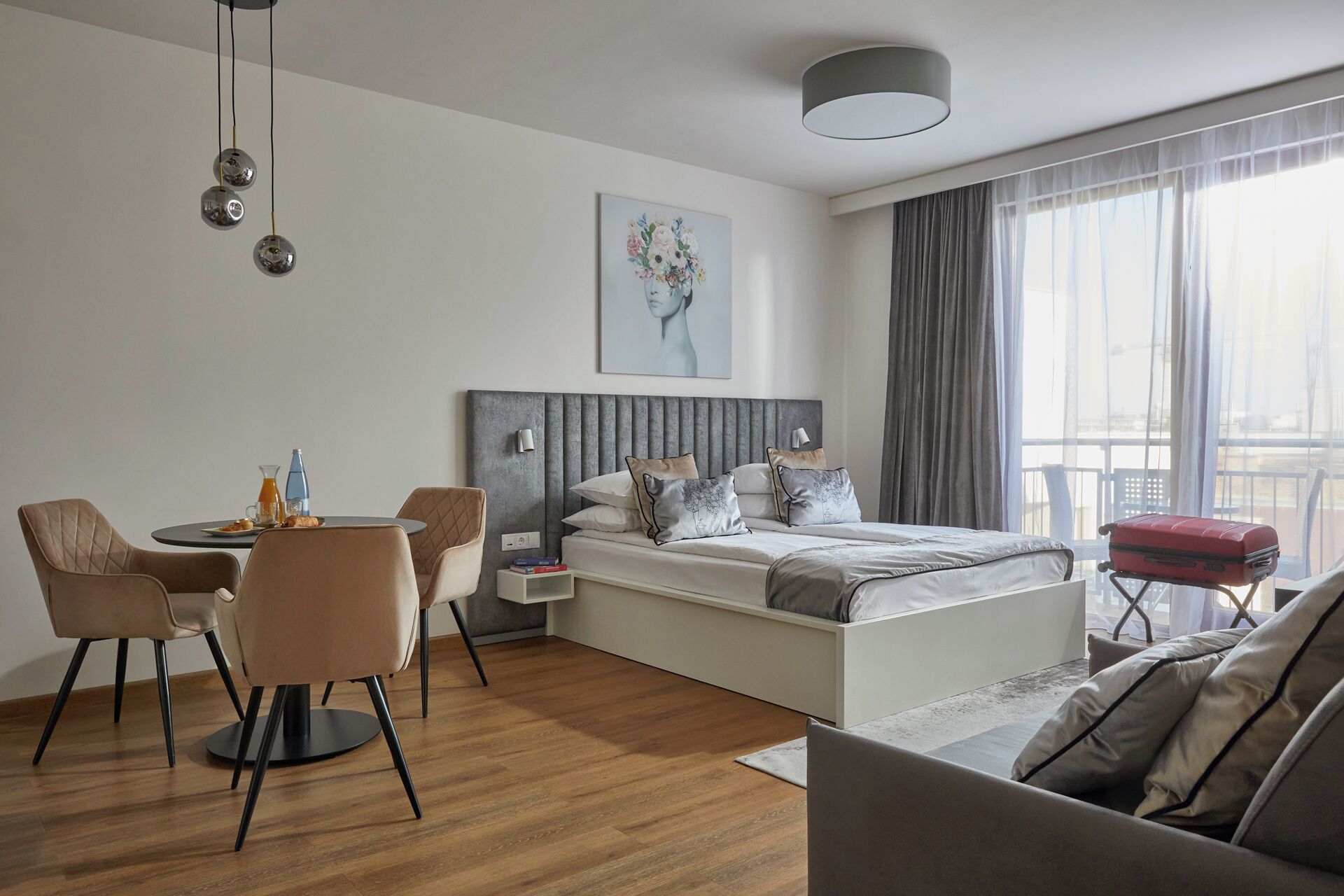 Quarto de hotel moderno com cama, área de refeições e sofá.