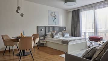 Quarto de hotel moderno com cama, área de refeições e sofá.