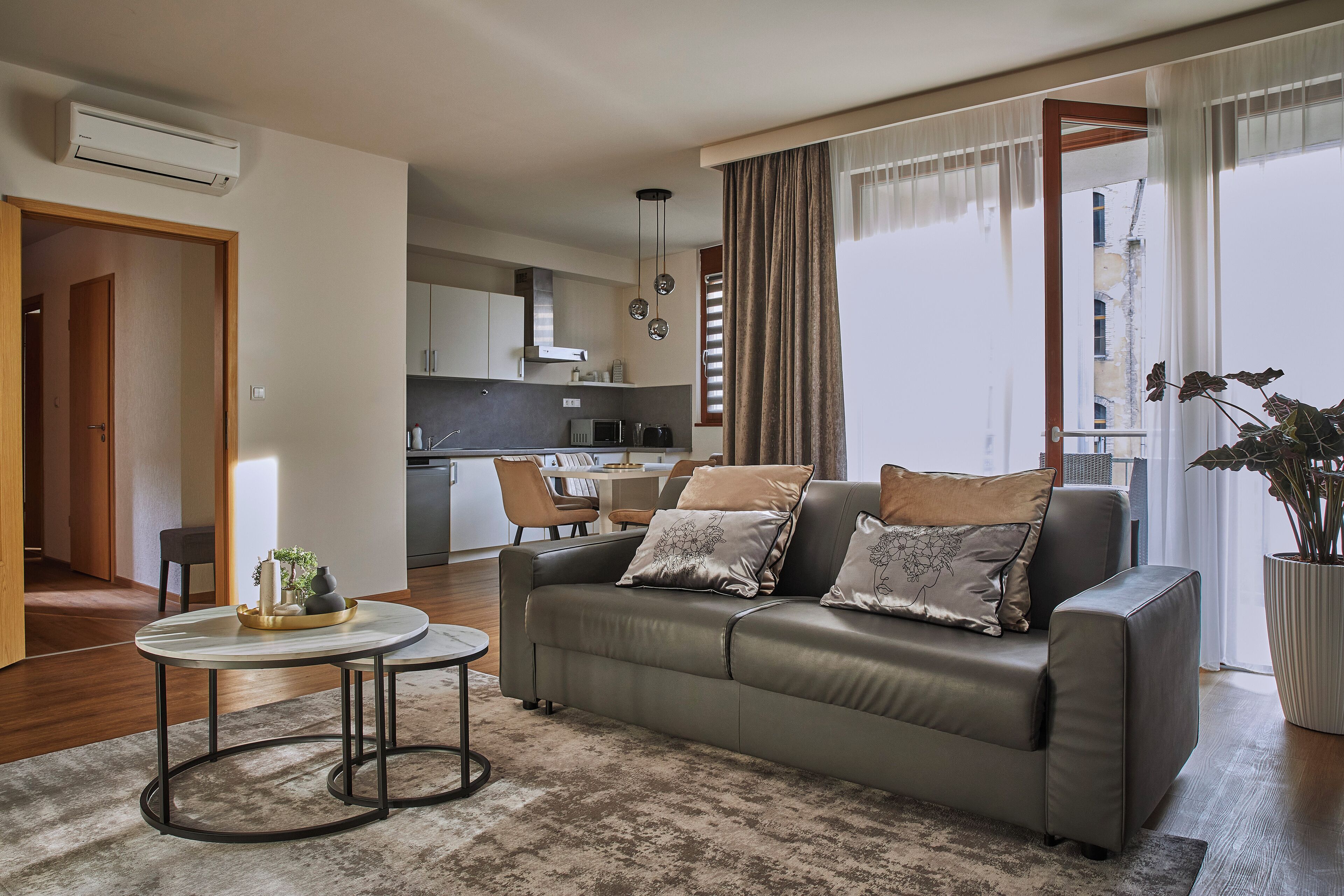 A modern living room with a sofa, a coffee table, and a dining area in the background.