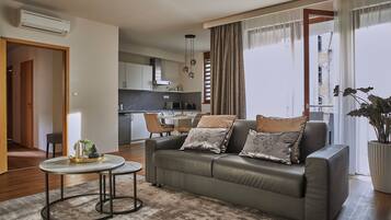 A modern living room with a sofa, a coffee table, and a dining area in the background.