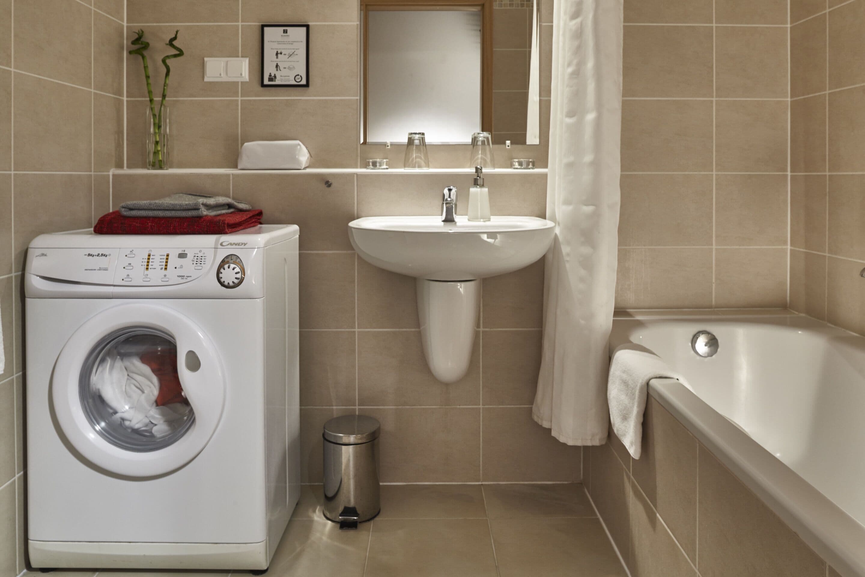 A modern bathroom with a washing machine, sink, and bathtub.