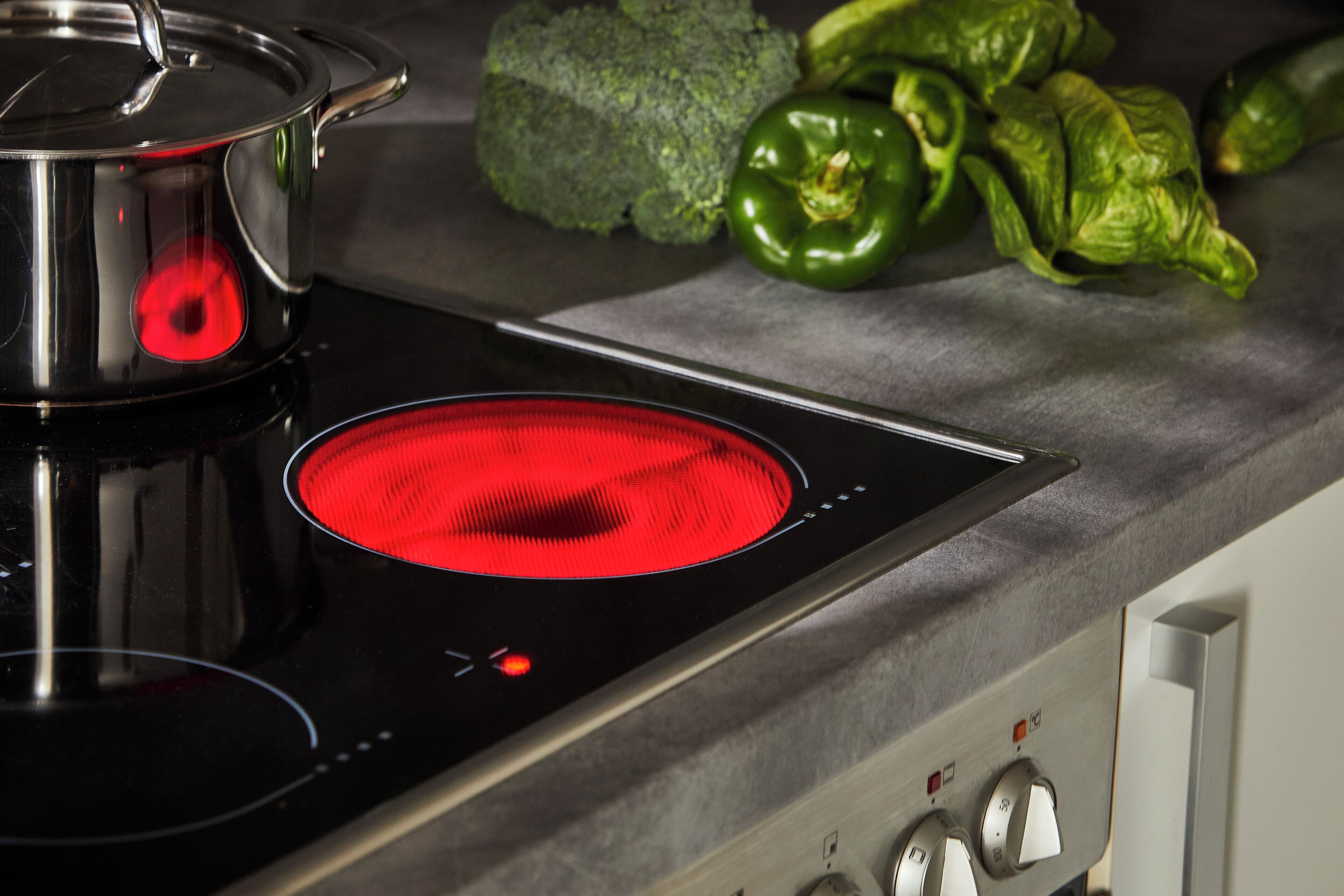 Een keuken met een zwart inductiekookplaatje en een pan erop.