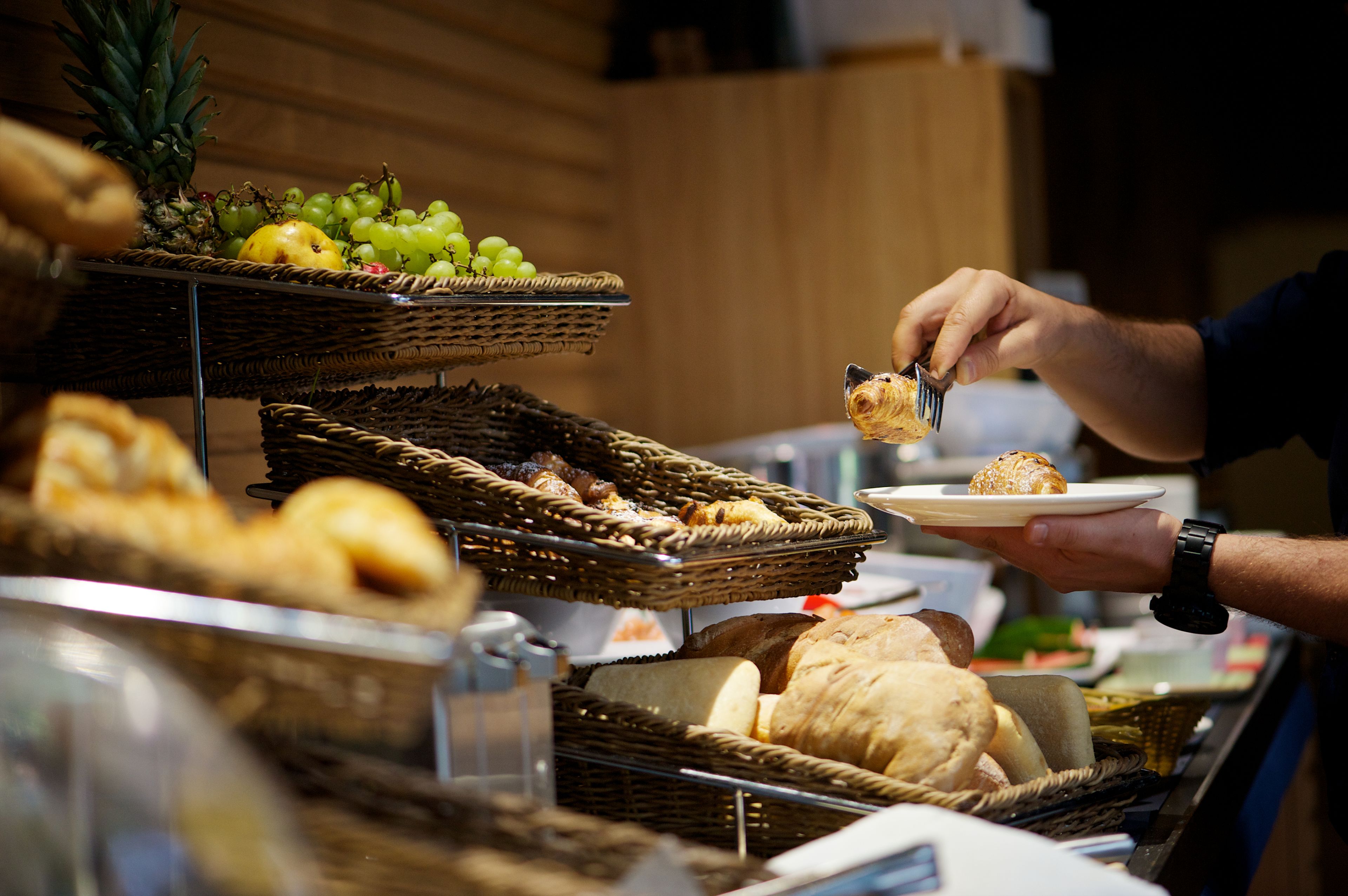 A buffet with various food items including bread, pastries, and fruits.