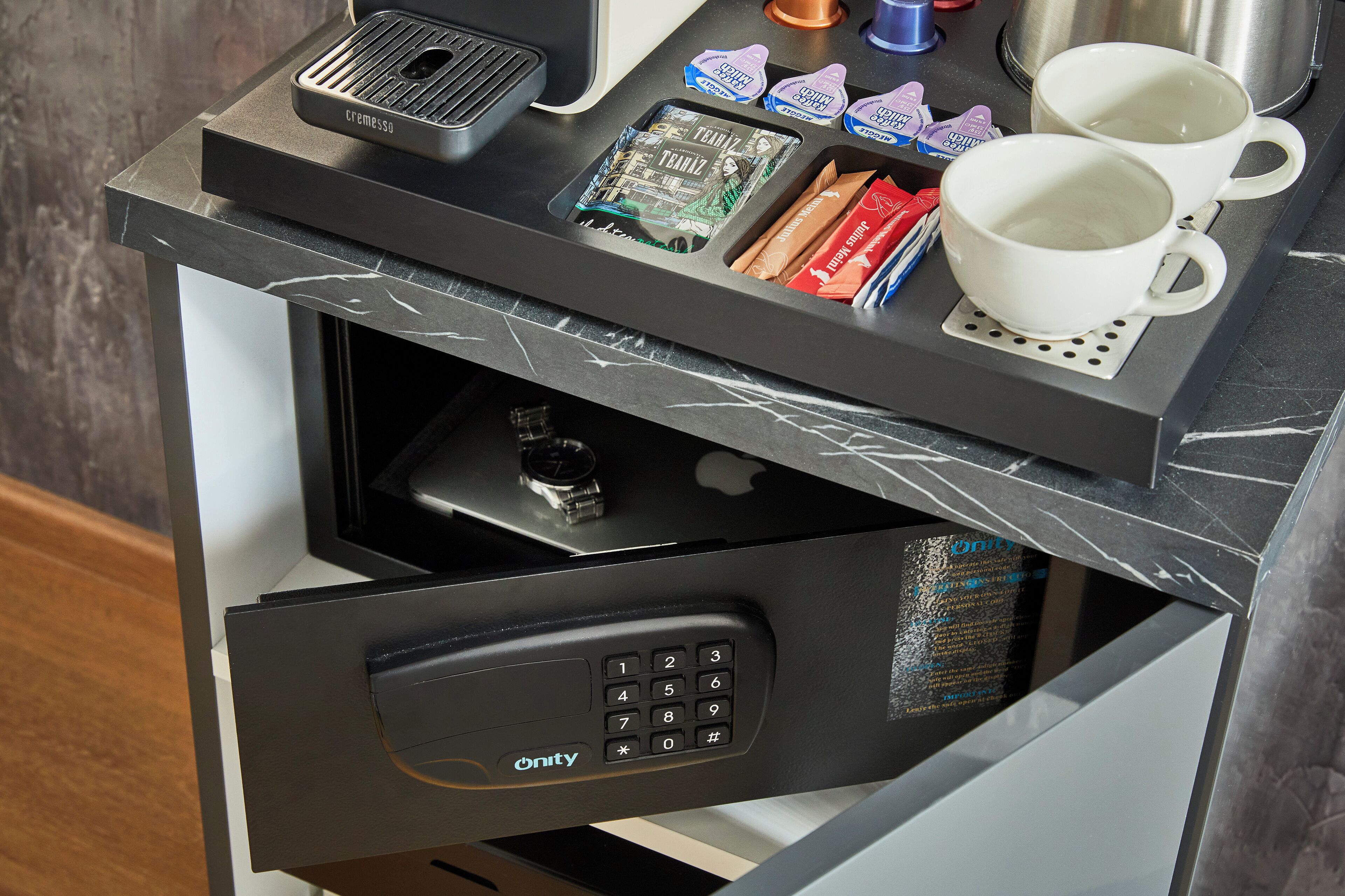 A coffee machine, two white cups, and a tray with coffee pods on a counter.