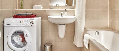 Une salle de bain moderne équipée d’un lave-linge, d’un lavabo et d’une baignoire.
