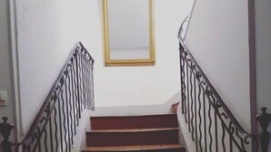 Eine Treppe mit Metallgeländern und einem goldgerahmten Spiegel an der Wand.