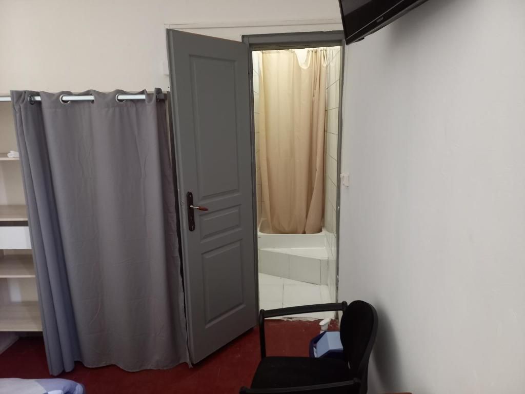 Ein Zimmer mit einer Tür zu einem Badezimmer, einem Stuhl und einem Regal.