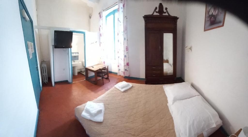 Un dormitorio con cama, un armario de madera, un escritorio con silla y un televisor.