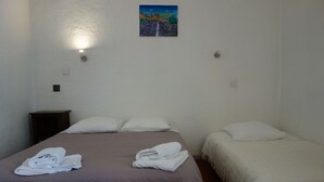 Ein Zimmer mit zwei Betten, einem Bild an der Wand und einer Nachttischlampe.