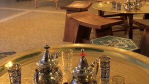A dining area with a traditional table set with silverware and blue-patterned glasses, surrounded by wooden chairs and a decorative wall mural. - Casa Baños de la Villa (Priego de Córdoba)