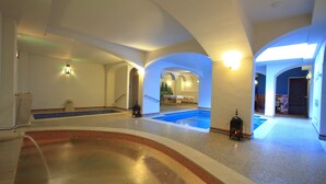 A large indoor swimming pool with multiple lanes, surrounded by white walls and arches, and a separate hot tub area. - Casa Baños de la Villa (Priego de Córdoba)