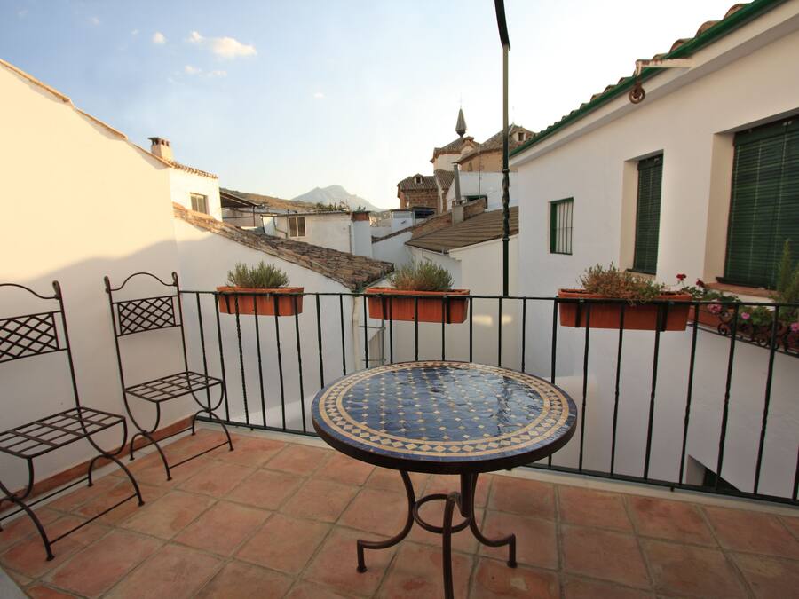 A patio with a round table, metal benches, and potted plants.