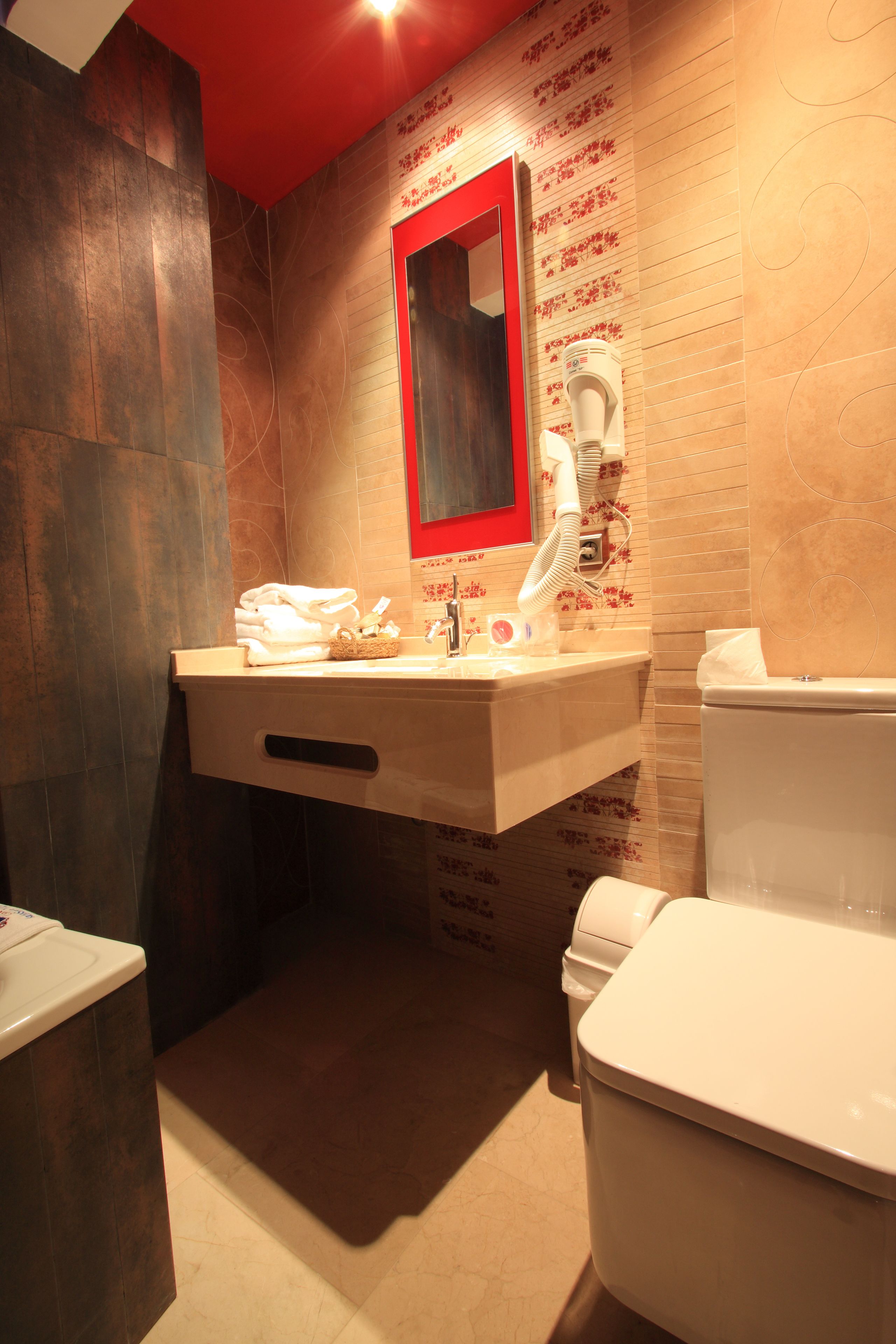 Un baño con lavamanos, espejo e inodoro.