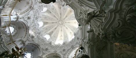 An ornate ceiling with intricate carvings and a central fanlight.