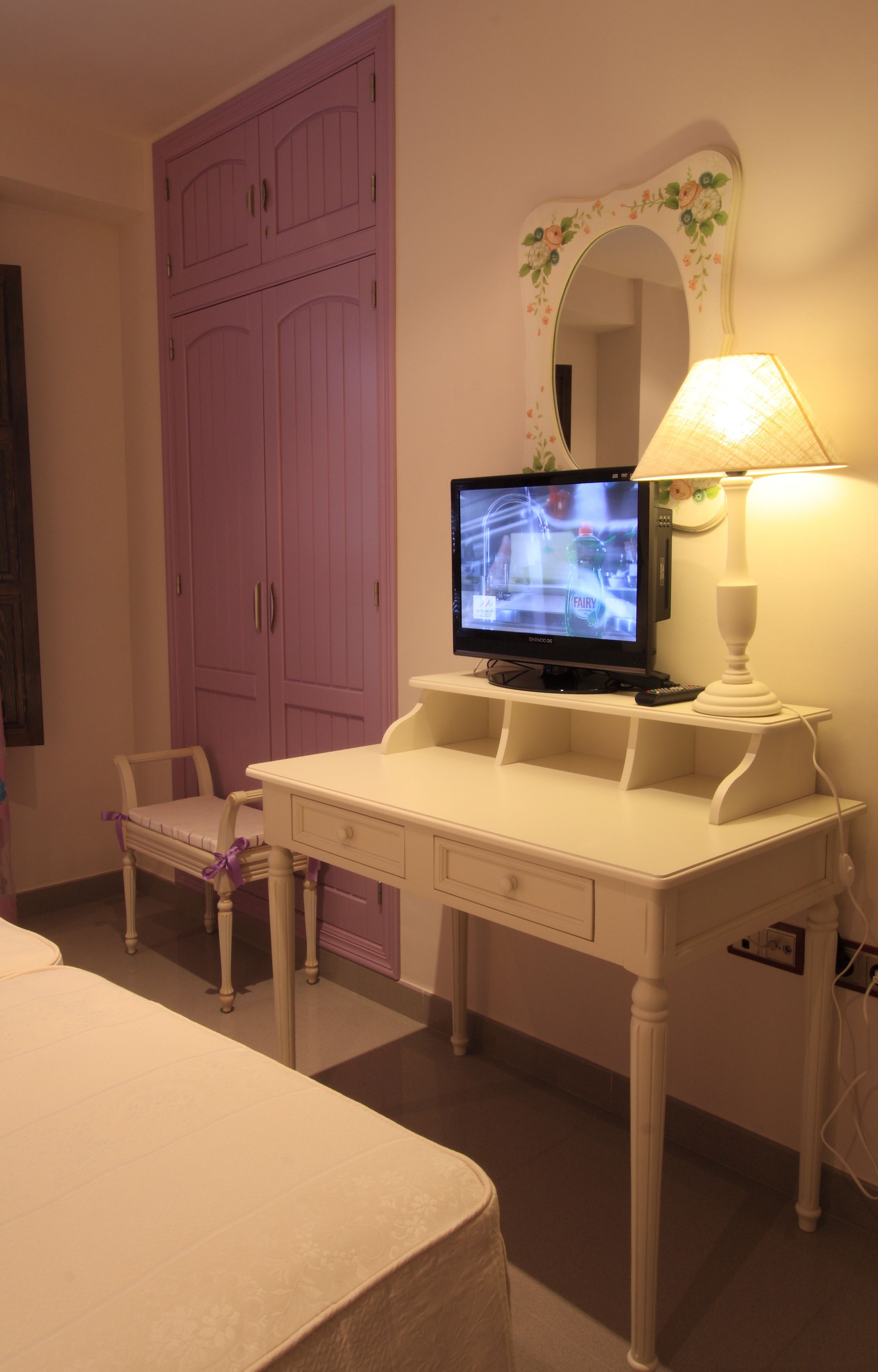 Une chambre à coucher avec un lit, une commode, un téléviseur et un miroir.