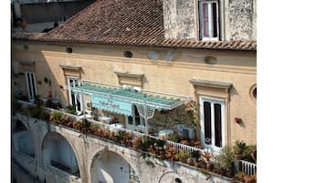 A building with a tiled roof, a balcony with potted plants, and a sign that reads "Regina Fratelli".
