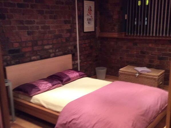 A single bed with a wooden headboard in a room with brick walls. - Trafalgar Warehouse Apartments (Liverpool)